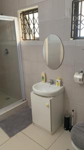 a white bathroom with a sink and a mirror at 56 Archer Crescent Mainhouse in Durban