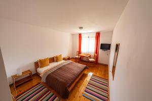 a bedroom with a bed and a table and a window at Pensiunea Tiuta in Corbeni