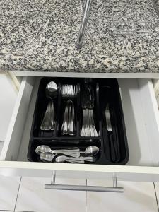 a tray of silver utensils in a kitchen drawer at Aconchegante apto no Centro! in Concordia +11 photos