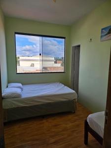 ウバジャラにあるCasa Mandacaruのベッドと大きな窓のある寝室