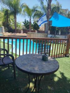a patio table with an umbrella next to a pool at Aloha House in Gan Shemuʼel