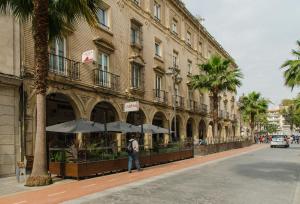 un hombre caminando por una calle al lado de un edificio con sombrillas en Costa De La Luz, en Huelva