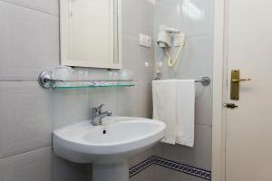 Un baño blanco con lavabo y espejo. en Costa De La Luz, en Huelva