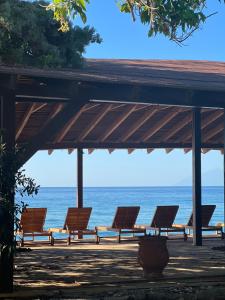 a row of chairs sitting under a pavilion near the ocean at hellofrom Beach House in Loutrá Elevtherón