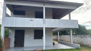 a white house with a door and a brick wall at Gray house in Paracuru