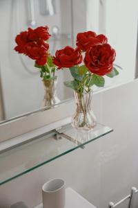 Un jarrón lleno de rosas rojas sobre un estante. en 24 Duomo - Camera centralissima, en Florencia
