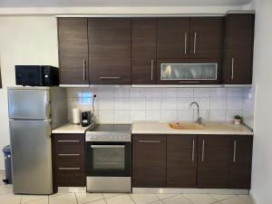 a kitchen with wooden cabinets and a stainless steel refrigerator at Angel Apartment in Poligiros +5 photos