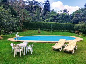 a pool with chairs and a table and a statue at Pousada dos Chalés - Araras in Araras Petropolis