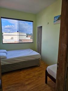 ウバジャラにあるCasa Mandacaruのベッドが2つと大きな窓がある寝室