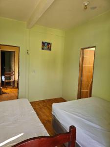 ウバジャラにあるCasa Mandacaruのベッドルーム1室(ベッド2台付)、木製のドアが備わります。