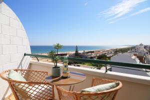 een balkon met een tafel en stoelen en de oceaan bij Seaside Lovers in Monte Gordo