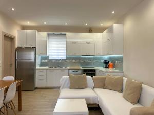 a living room with a white couch and a kitchen at Ledjon apartament in Artemida +11 photos
