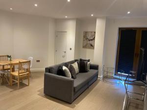 a living room with a gray couch and a table at Extra large spacious 1 Bedroom private apartment, Nr St Albans City Station, Business, contractor, Parking, WiFi in Saint Albans +4 photos