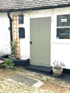 a green door on a white house with plants at Petworth Cottage-Sleeps 6-Pet Friendly-Central in Petworth