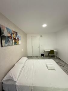 a bedroom with a large white bed and a desk at Nova Rooms in Madrid