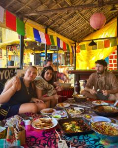 a group of people sitting around a table with food at Mandala House - Party hostel in Palolem +58 photos