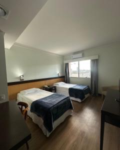 a hotel room with two beds and a window at Villa Vergueiro Hotel in Passo Fundo