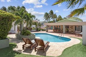 una piscina con dos sillas y una casa en WLR5 - Studio near Palm Beach - White Lotus Retreat, en Palm-Eagle Beach