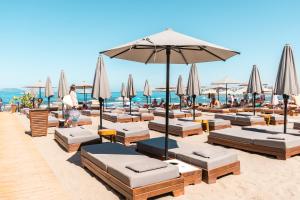 a beach with lounge chairs and an umbrella and the ocean at Yacht Hotel in Vlorë