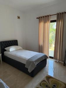 a bedroom with a bed and a large window at Quiet Room, close to Airport in Kamëz