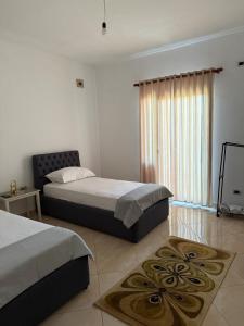 a bedroom with two beds and a large window at Quiet Room, close to Airport in Kamëz