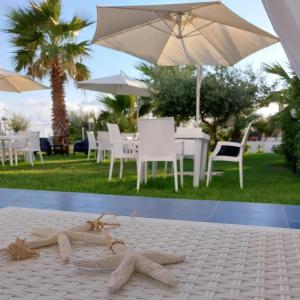 two pairs of sandals sitting on a table with an umbrella at B&B Il Gabbiano in Cittadella del Capo