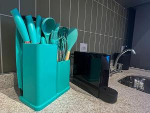a green container with utensils on a counter next to a sink at Loft - Conforto e Design - Vila Mariana in Sao Paulo +12 photos