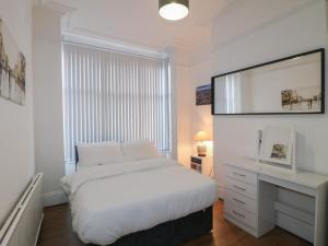 a white bedroom with a bed and a desk at 2 Evington Road in Leicester
