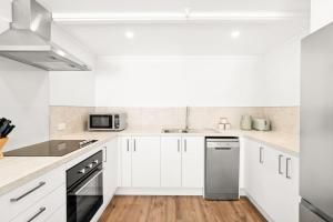 a white kitchen with white cabinets and appliances at Central on Shotover 2 in Queenstown +13 photos