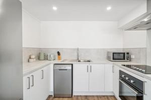 a kitchen with white cabinets and a stainless steel dishwasher at Central on Shotover 1 in Queenstown +12 photos