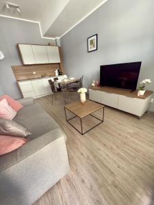 a living room with a couch and a flat screen tv at Sunset A23 przy plaży in Pobierowo