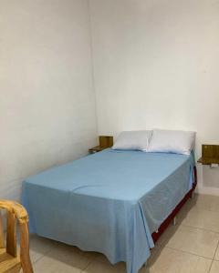 Una cama en una habitación con una manta azul encima. en Hospedagem em Canasvieiras - Pé na Areia com Vista para o Mar, en Florianópolis