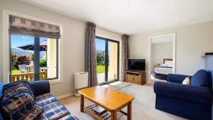 a living room with a couch and a tv and a bed at Warm and spacious 2 bedroom, downstairs apartment in Wanaka