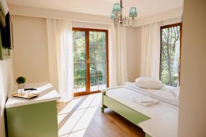 a bedroom with a bed and a desk and windows at PENSIUNE RESTAURANT POIANA AVRIGULUI loc de joaca pentru copii in Avrig +194 photos
