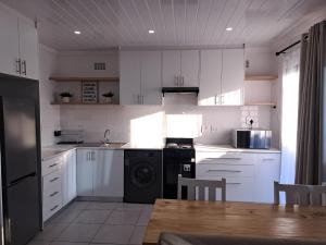 a kitchen with white cabinets and a sink and a table at Garden studio flat in Panorama +3 photos