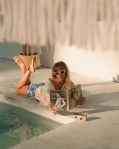 a girl laying next to a swimming pool reading a book at Bailan Byron Serene Luxury Villa in Ewingsdale
