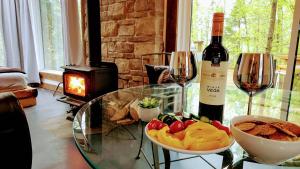 a glass table with a bowl of fruit and a bottle of wine at La Cache de l'Ours - Thermal Experience Spa&Sauna in Saint-Alexis-des-Monts