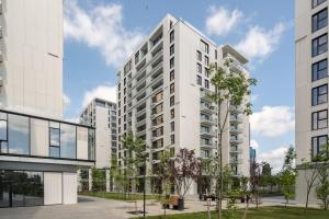 Ace of Hearts 1 BR APARTMENT,Parking, Fast wi-fi in One Cotroceni في بوخارست: مبنى أبيض طويل وبه أشجار أمامه