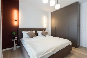 Ace of Hearts 1 BR APARTMENT,Parking, Fast wi-fi in One Cotroceni في بوخارست: غرفة نوم بسرير كبير مع ملاءات ووسائد بيضاء