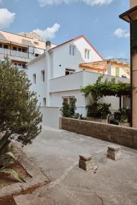 a white apartment building with a driveway and trees at Villa Dora in Omiš centar now with Jacuzzi in Omiš