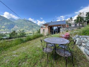 stół i krzesła na polu z domem w obiekcie La Grange des Eulets w mieście Bourg-Saint-Maurice
