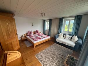 a room with a bed and a couch and a window at Ferienhof Mitterbauer in Mondsee