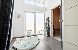 Una bañera en un baño con una ventana grande. en Awesome Home In Glesborg With Sauna, en Glesborg