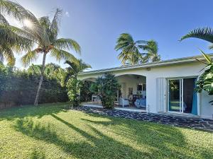 a white house with palm trees and a yard at Villamarday - Coquette villa privée au bord de l'océan in Pointe aux Cannoniers