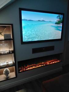 a flat screen tv hanging above a fireplace in a living room at Macaldrack's Loft in Dunloy