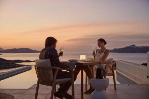 two people sitting at a table with wine glasses at Hotel Milos Sea Resort in Adamantas