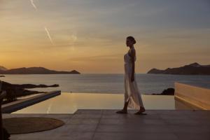 a man standing on the edge of a pool with the ocean at Hotel Milos Sea Resort in Adamantas