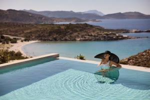 a woman in a hat sitting in a swimming pool at Hotel Milos Sea Resort in Adamantas
