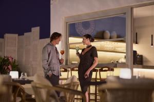 a man and a woman holding glasses of wine at Hotel Milos Sea Resort in Adamantas