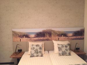 a bed with two pillows and a painting on the wall at France Hotel in Amsterdam
